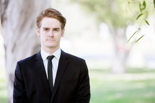 handsome man in a suit standing in park