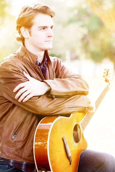 彼のギターと公園で座っているハンサムな男 — ストック写真