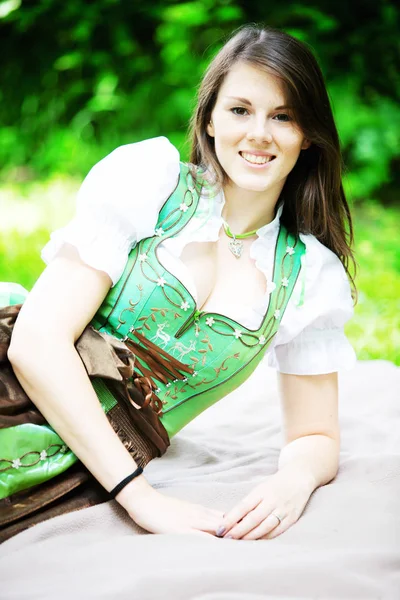 Junge Frau im Dirndl liegt auf Decke im Park — Stockfoto