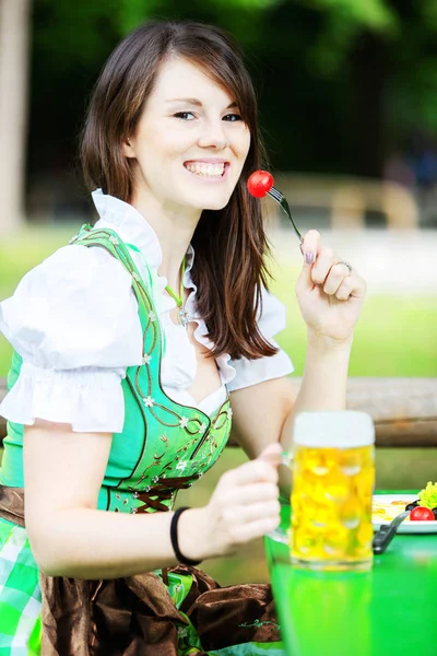 Portrét ženy v dirndl s pivem a jídlem — Stock fotografie