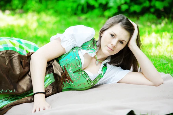 Fiatal nő a Dirndli takaró parkban fekvő — Stock Fotó
