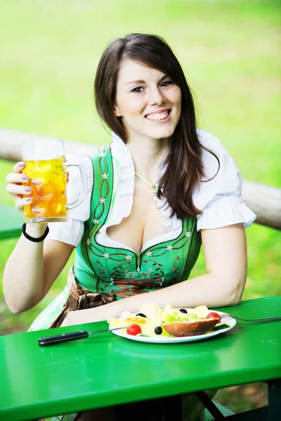 Portret van een vrouw in dirndl met bier en voedsel — Stockfoto