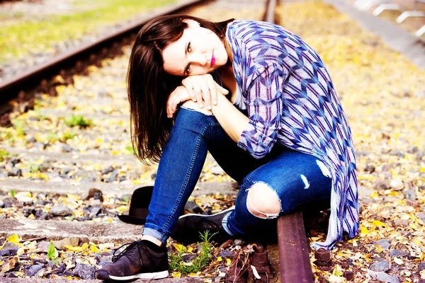 Porträtt av vackra sorgliga kvinna sitter på järnvägsspåren — Stockfoto