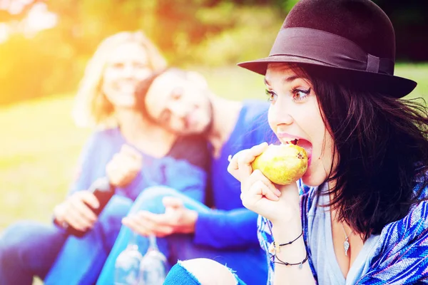 Jeune femme manger une poire et pique-niquer avec des amis — Photo