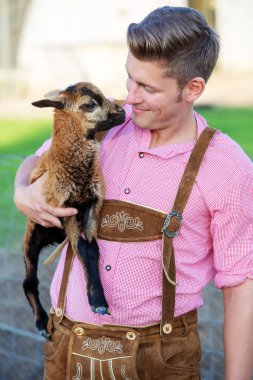 sarışın Bavyera adam küçük bir keçi holding
