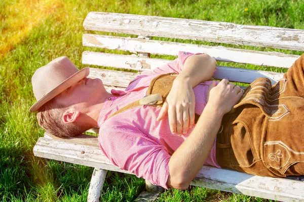 Biondo bavarese uomo dormire all'aperto su un panchina — Foto Stock