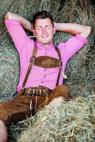 Knappe Beierse man slapen in het hooi — Stockfoto