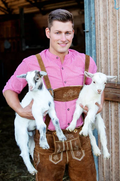 2 つの小さな白いヤギを抱きかかえた金髪バイエルン — ストック写真