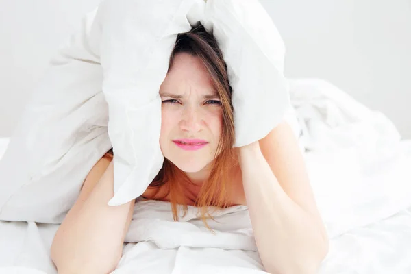 Mujer joven acostada en la cama con dolor de cabeza —  Fotos de Stock