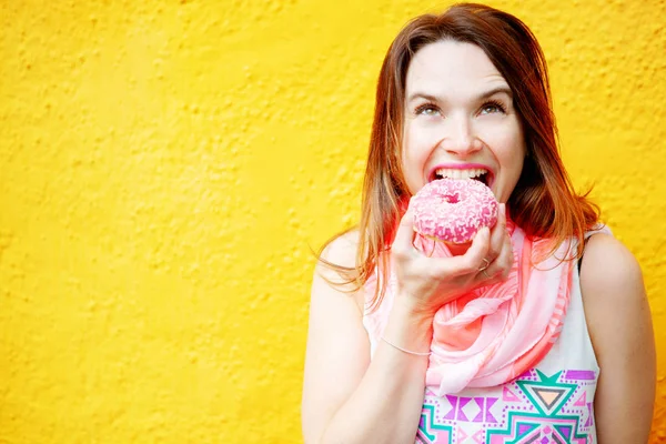 Junge brünette Frau isst einen Donut — Stockfoto