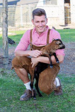 sarışın Bavyera adam küçük bir keçi holding