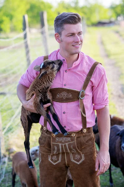 小さなヤギを抱きかかえた金髪バイエルン — ストック写真