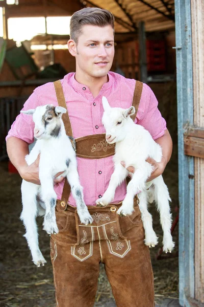 2 つの小さな白いヤギを抱きかかえた金髪バイエルン — ストック写真