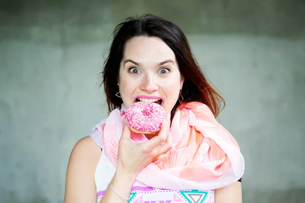 Jonge brunette vrouw eten van een donut — Stockfoto