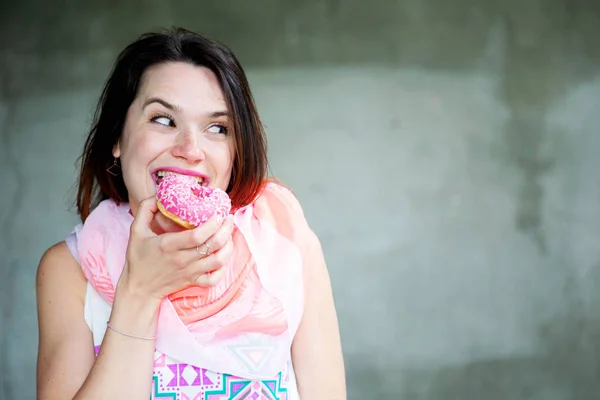 Mladá bruneta žena jíst koblihy — Stock fotografie