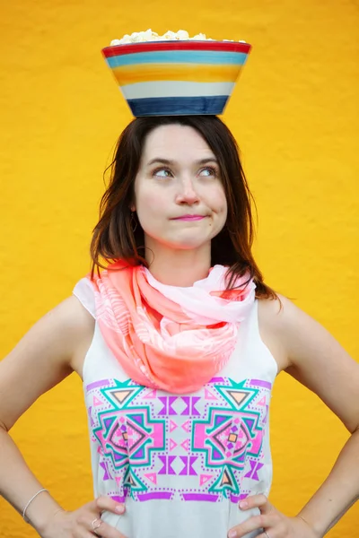 Jonge brunette vrouw met kom popcorn op haar hoofd — Stockfoto