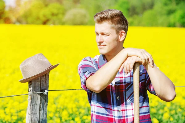 Homem bonito com forquilha em pé na frente do campo amarelo — Fotografia de Stock