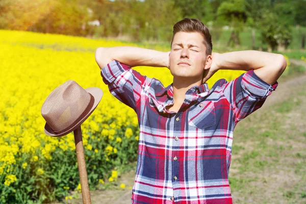 Bell'uomo biondo davanti al campo giallo che si gode il sole — Foto Stock
