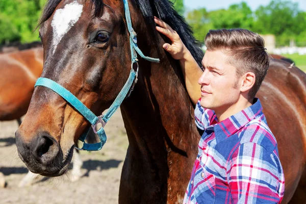 Handsome blond man with brown horse outdoors — Stock Photo, Image