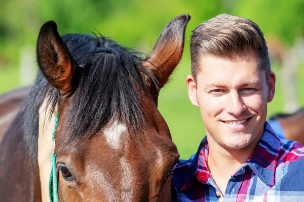 Handsome blond man with brown horse outdoors — Stock Photo, Image