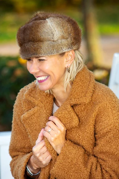 Femme blonde assise sur un banc dans le parc et profitant du soleil d'automne — Photo