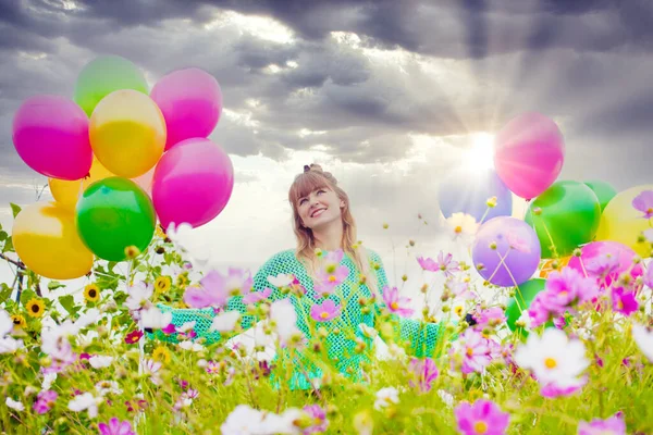 年轻的女人站在花坛上 拿着彩色的气球 — 图库照片