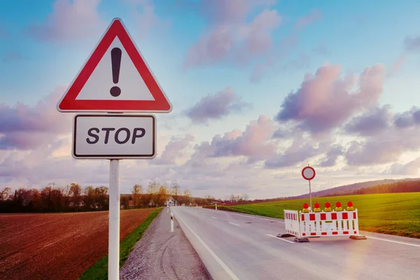 road block with street sign and warning lights on road at countryside