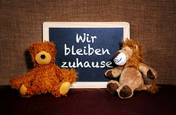 两只泰迪熊在黑板旁边 上面写着德语 我们呆在家里 — 图库照片