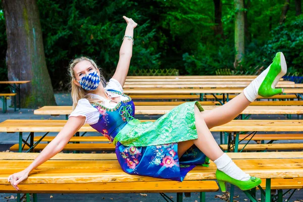 Mulher Dirndl Vestindo Uma Máscara Facial Azul Branco Sentado Jardim — Fotografia de Stock