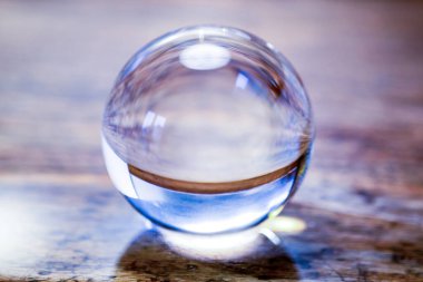 close-up of beautiful glass sphere on a rustic wooden table clipart