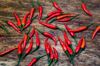 Kırsal ahşap bir masaya yayılmış kırmızı biber demeti.