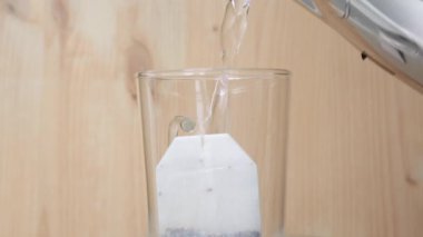 Çay poşeti sıcak suyla dönen tabağa dökülen çay bardağının yakın çekimi.