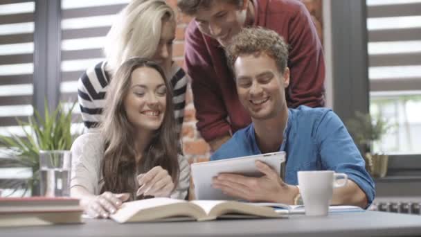 Vier studenten bezig met hun huiswerk met behulp van tablet pc. — Stockvideo