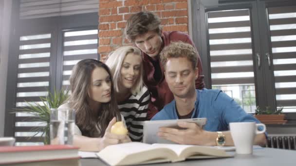 Cuatro estudiantes que trabajan en sus tareas usando Tablet PC . — Vídeos de Stock
