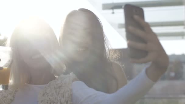 Két fiatal nő szelfit készít mobiltelefonnal. — Stock videók