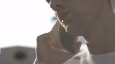 Yakışıklı genç adamın kasabadaki telefonda konuşurken profil görünümü.