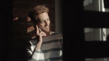 Modern çatı katında akıllı telefon iç konuşurken düşünceli yakışıklı genç. 