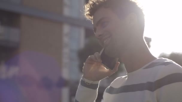 Vista del perfil del joven guapo hablando por teléfono en la ciudad . — Vídeo de stock