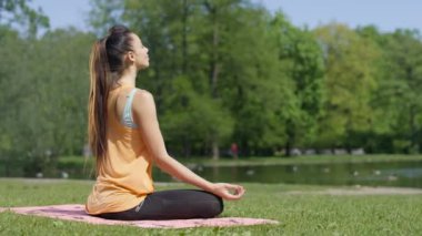 Genç kadın güneşli park, dikiz meditasyon. 
