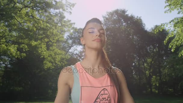 Jovem mulher bonita meditando no parque ensolarado . — Vídeo de Stock