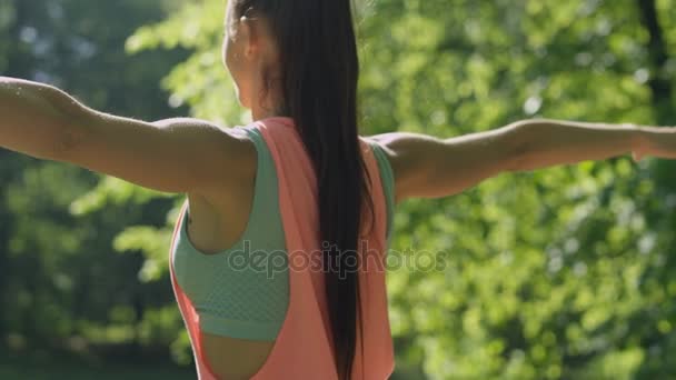 Молода жінка робить вправи і розтягується в сонячному парку в літній ранок . — стокове відео