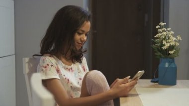 Evde cep telefonu kullanan genç bir kadın..
