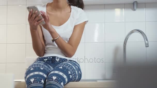 Young Afro American woman sitting in a kitchen and writting on mobile phone. — Stock Video