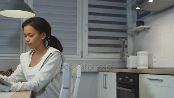 Güzel bir genç Afro-Amerikan kadın mutfağa bir tablet bilgisayar kullanarak. — Stok video