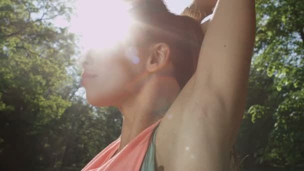 Молода жінка розтягується в сонячному парку . — стокове відео