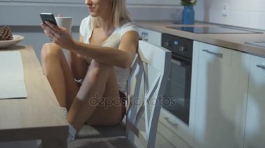 Telefon kullanarak ve evde rahatlatıcı genç güzel kız.