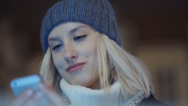 Mujer joven usando el teléfono móvil en una ciudad por la noche . — Vídeo de stock