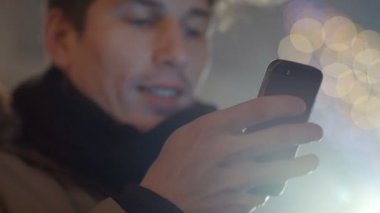 Geceleri cep telefonunu kullanan genç bir adamın açık hava portresi..