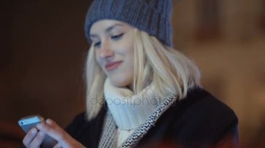 Cep telefonuyla bir şehirde gece genç kadın.