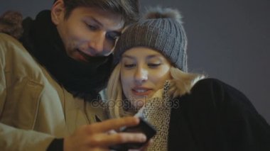 Genç çift smartphone cep telefonu ile fotoğraf geceleri bir şehirde sokak izliyor..